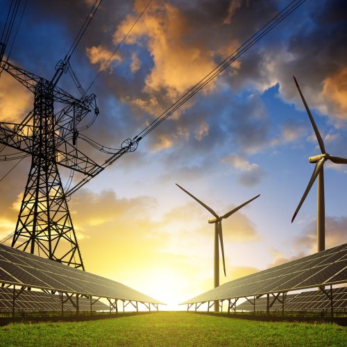 Solar panels with wind turbines and electricity pylon at sunset. Clean energy concept.